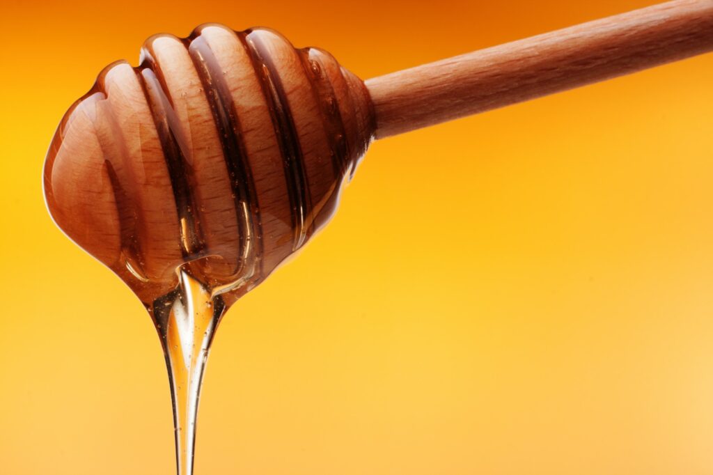 Honey dripping from a wooden honey
